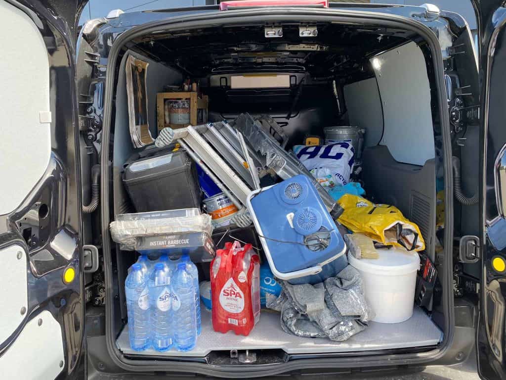 Lading van bedrijfswagen met bouwmaterialen en gereedschap voor bedrijfswageninrichting.