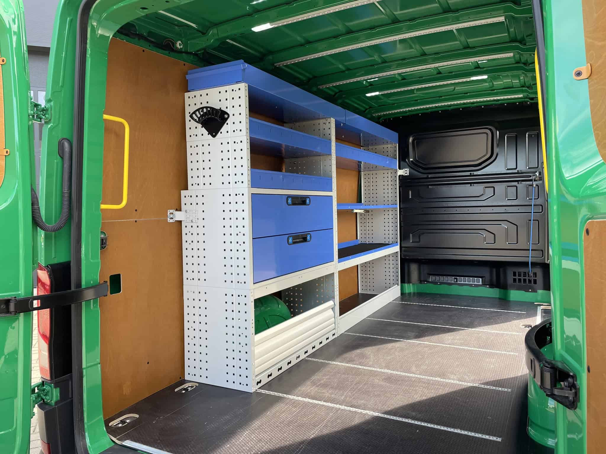 Lade- en opbergruimte voor bedrijfswagens met geaarde werkbanken en georganiseerde opbergkasten, ideaal voor professionele transport- en klusactiviteiten.