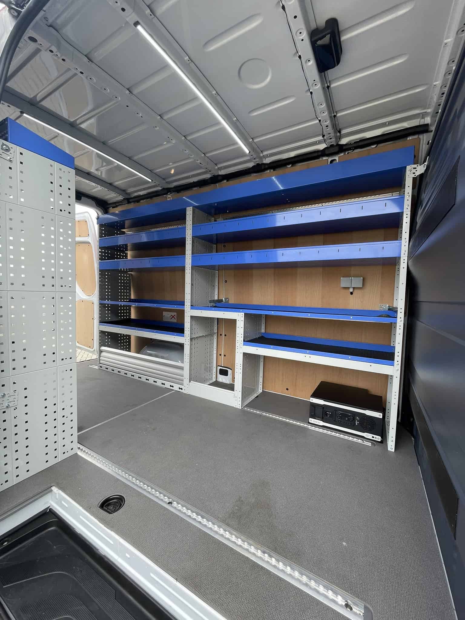 Gewilde bedrijfswageninrichting met stabiele blauwe en houten rekken, ideaal voor professionalisten, met voldoende opbergmogelijkheden en organisatie.
