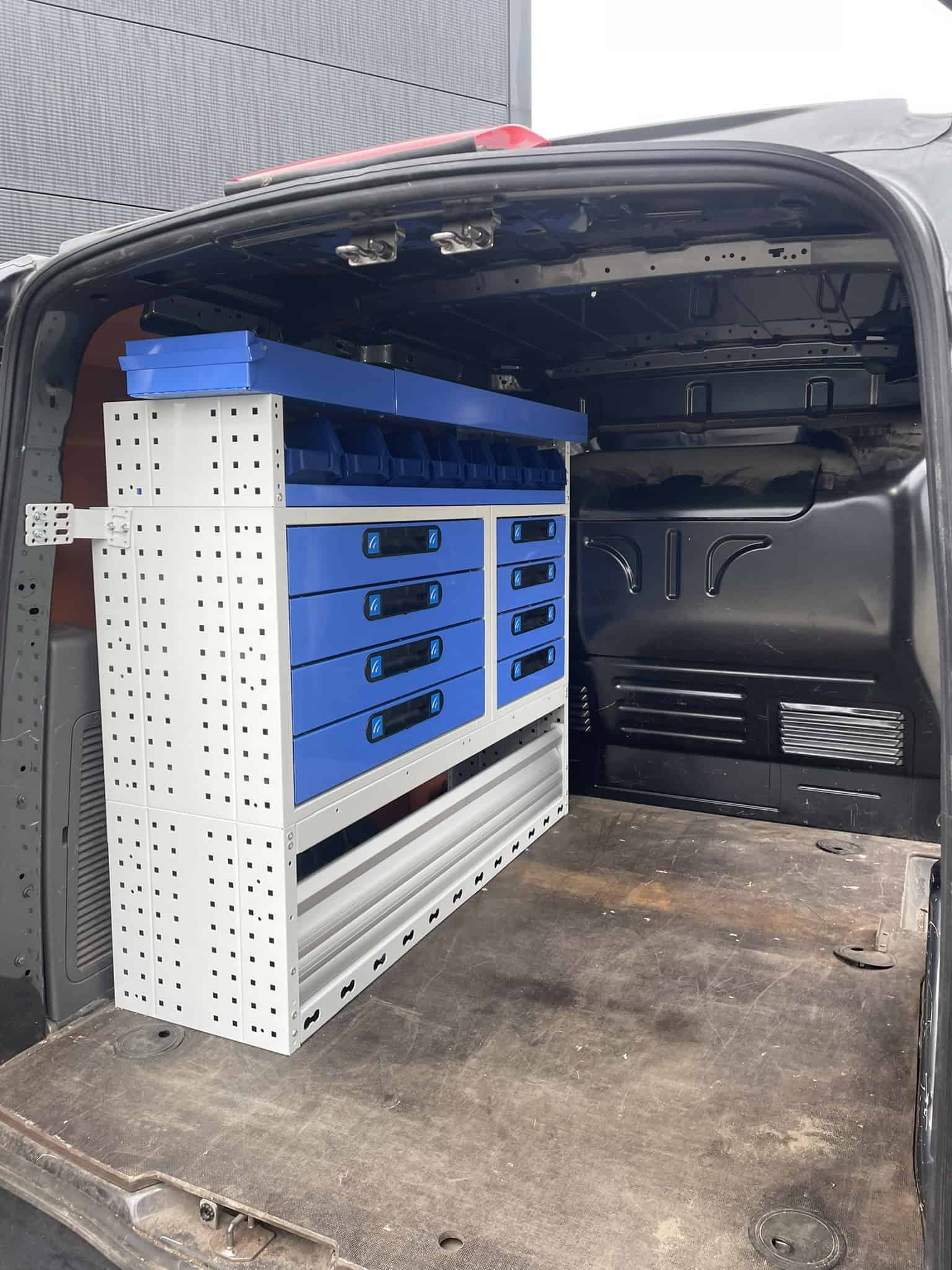 Kleuren en maatwerk bedrijfswageninrichting met opbergsystemen en gereedschapskisten in de laadruimte van een bestelwagen.