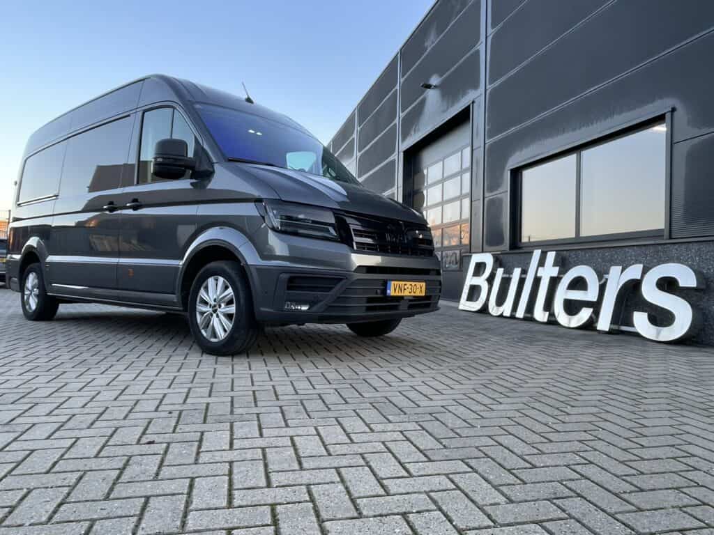 Zwart bedrijfsbus voor op maat gemaakte bedrijfswageninrichting, ideaal voor professioneel gebruik en opslag, geparkeerd voor een modern bedrijfsgebouw met "Butlers" logo, klaar voor zakelijk transport.