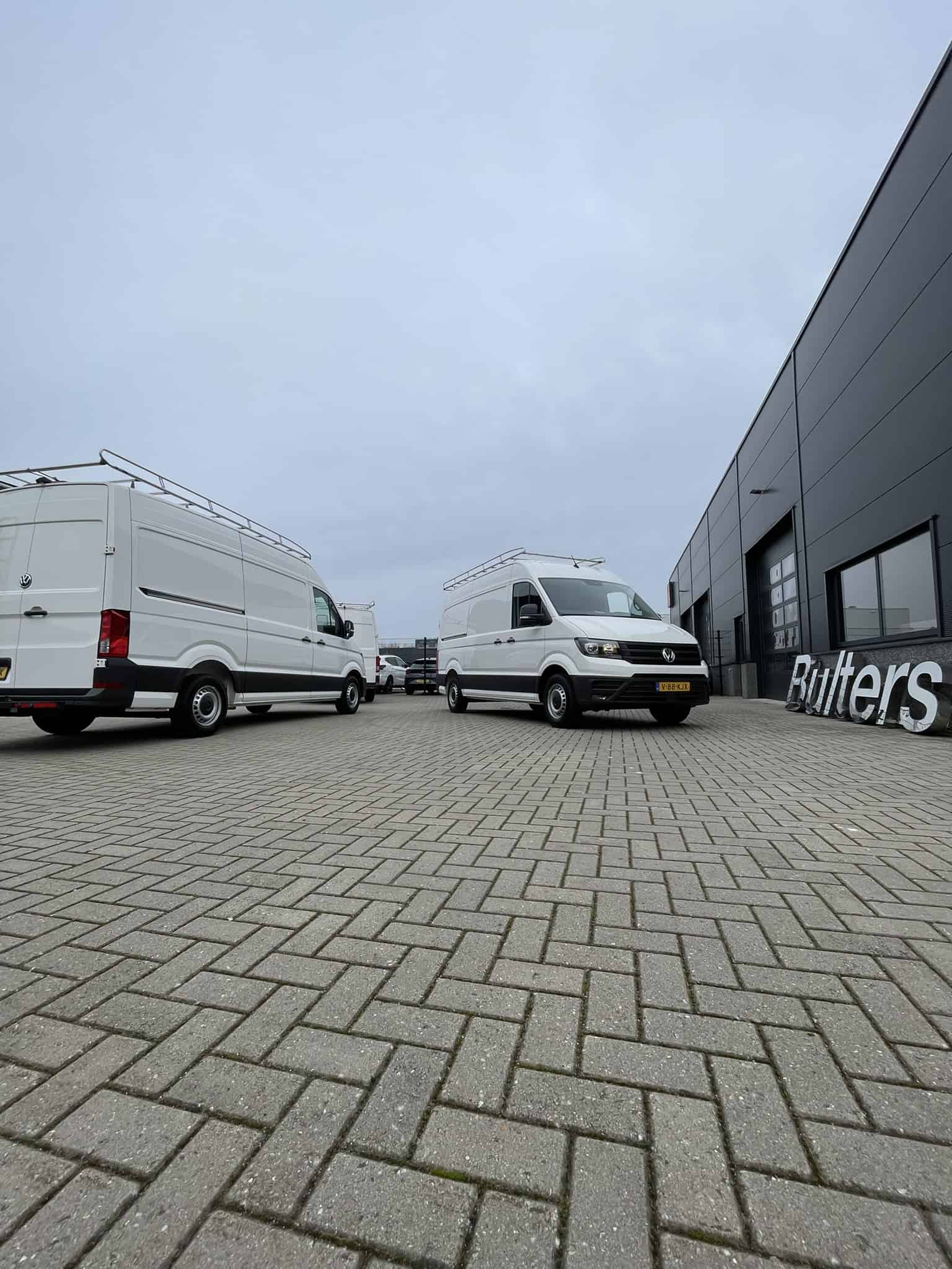 Drie bedrijfswagens geparkeerd voor een modern bedrijfsgebouw, geschikt voor logistiek en transport, met professionele inrichting en ruime laadcapaciteit.