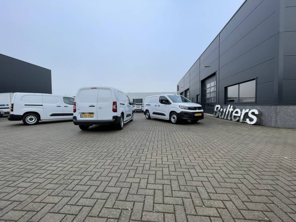 Drie bedrijfswagens geparkeerd voor het moderne bedrijfswageninrichtingsbedrijf, met op maat gemaakte interieuroplossingen voor bedrijfsvoertuigen.