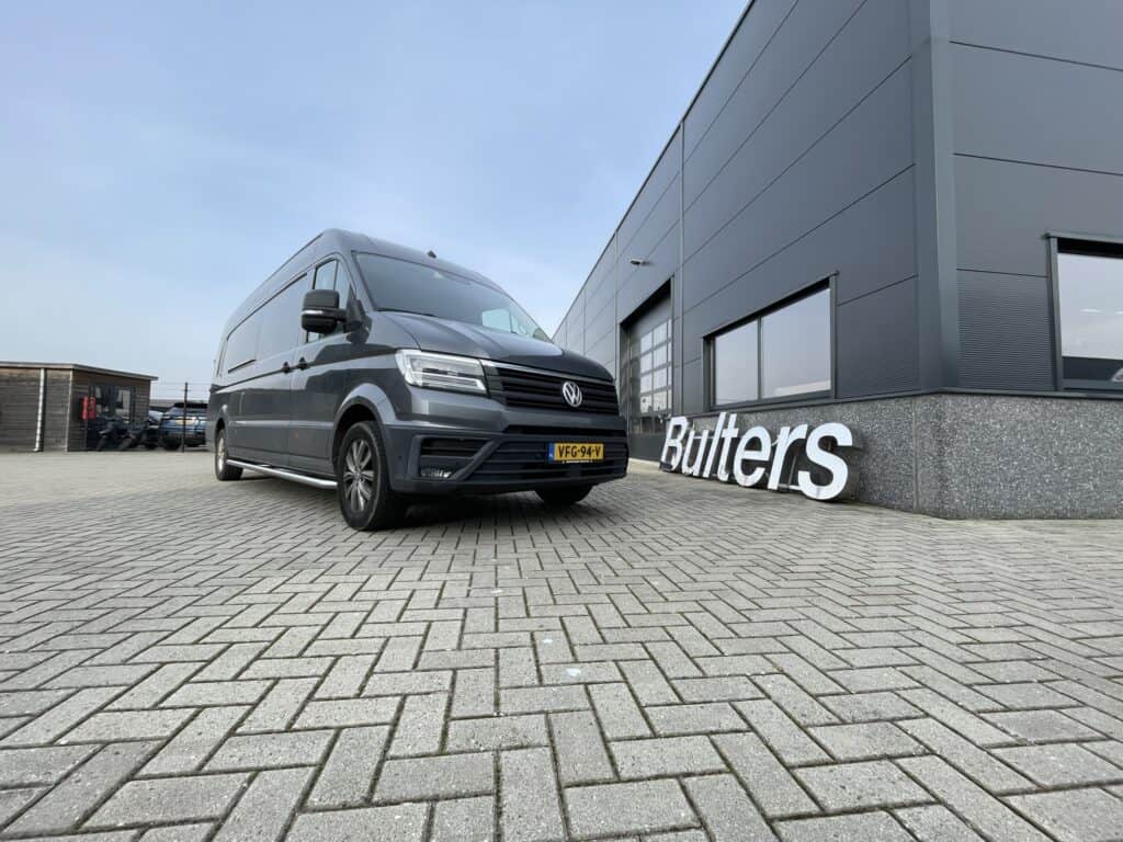 Moderne Volkswagen bedrijfswagen geparkeerd voor een bedrijfsgebouw, geschikt voor inbouw en bedrijfswageninrichting, met focus op functionaliteit en bedrijfsgebruik.