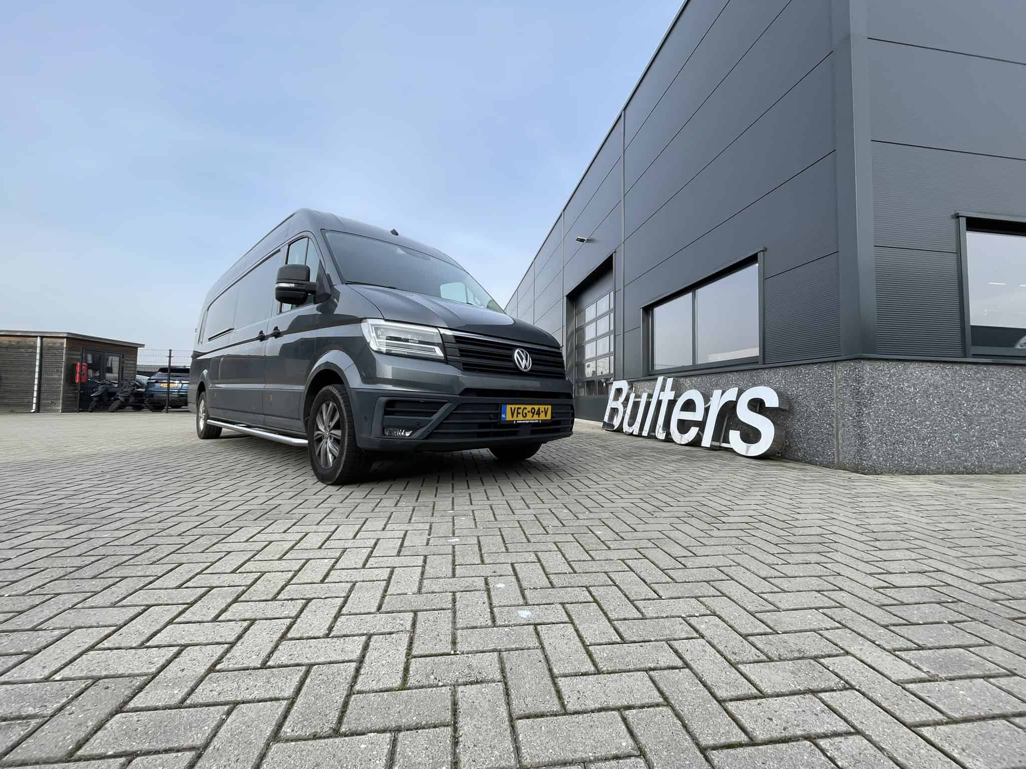 Moderne Volkswagen bedrijfswagen geparkeerd voor een bedrijfsgebouw, geschikt voor inbouw en bedrijfswageninrichting, met focus op functionaliteit en bedrijfsgebruik.