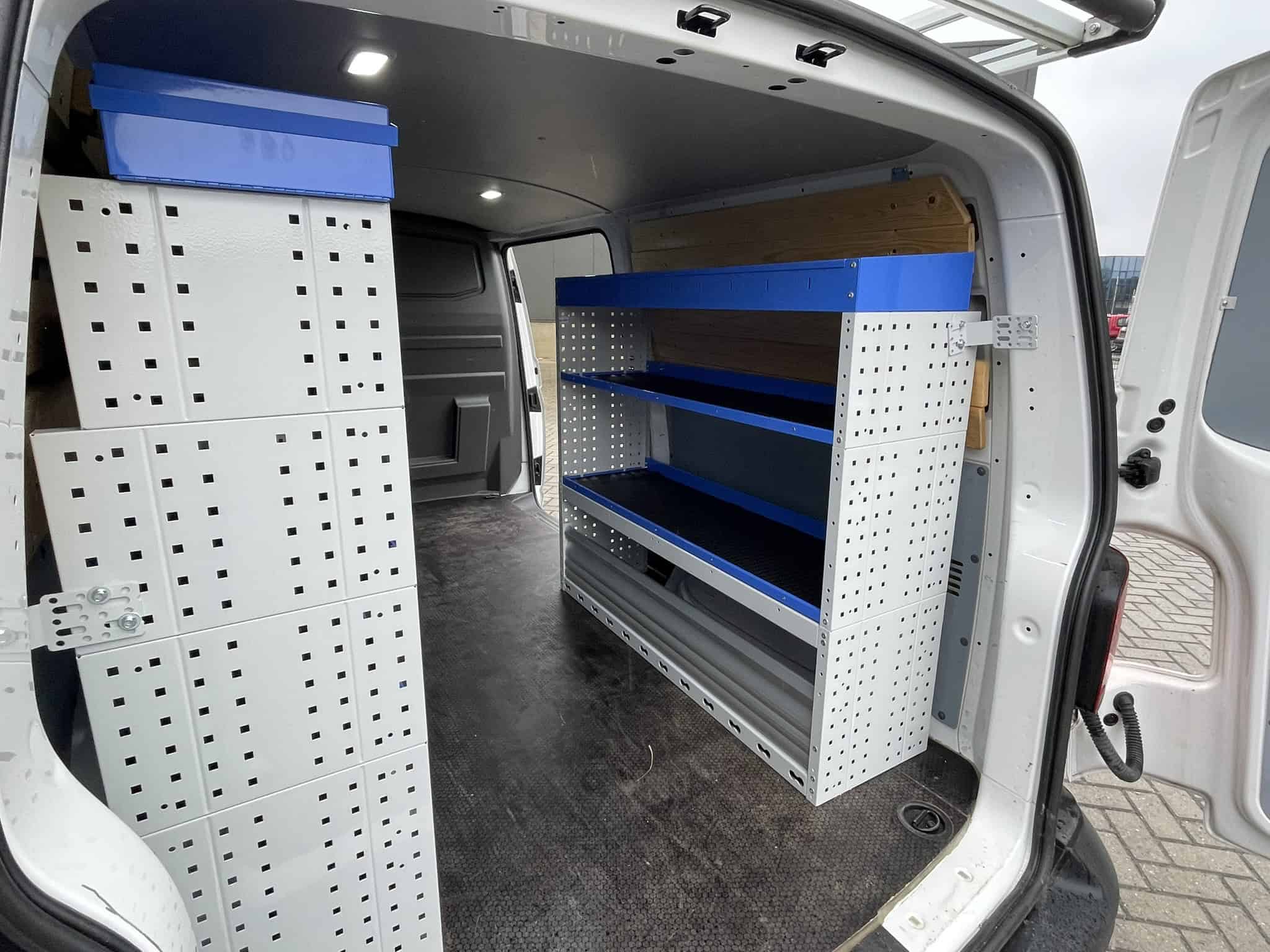 Interieur van een bedrijfswagen met opbergrekken en planken voor efficiënte opslag en organisatie van gereedschap en materialen.