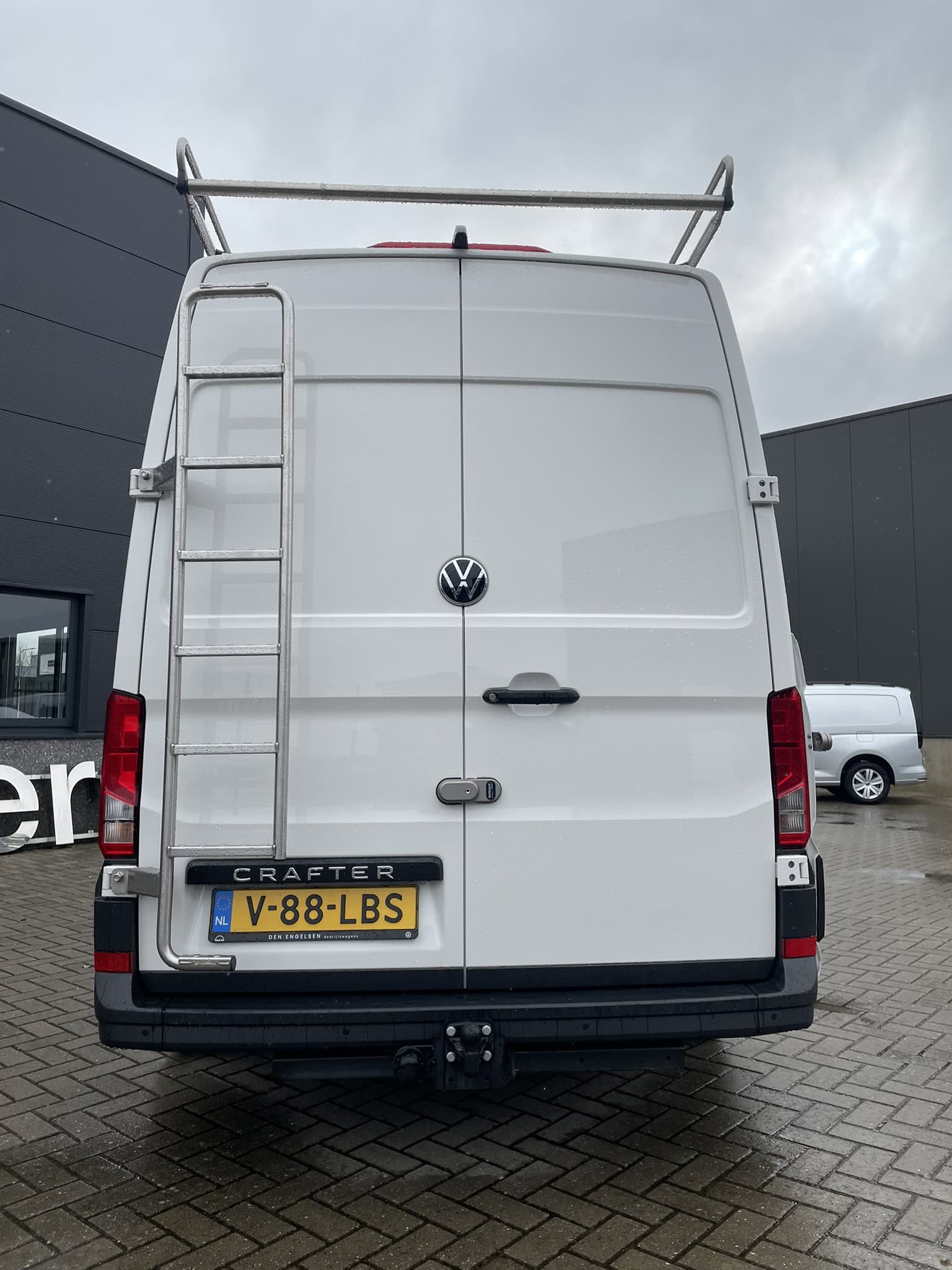 Moderne bedrijfswagen met ladder en dakrek, ideaal voor bedrijfsinrichting en transport. Geschikt voor het vervoeren van materialen en gereedschap, met een ruime laadruimte en stevige constructie.