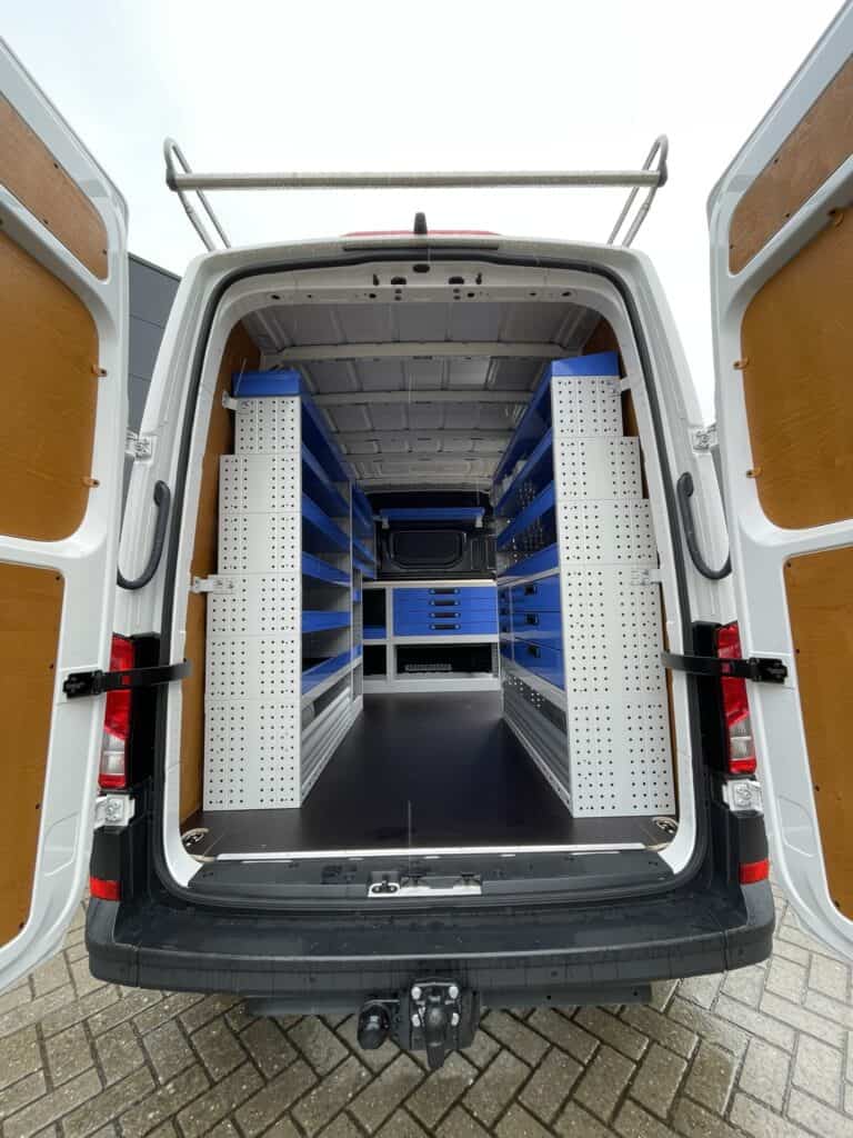 Interieur van een bedrijfswagen met georganiseerde werkplaatsinrichting, inclusief blauwe opbergrekken en werkbladen, ideaal voor vakmensen en bedrijfsgebruik.
