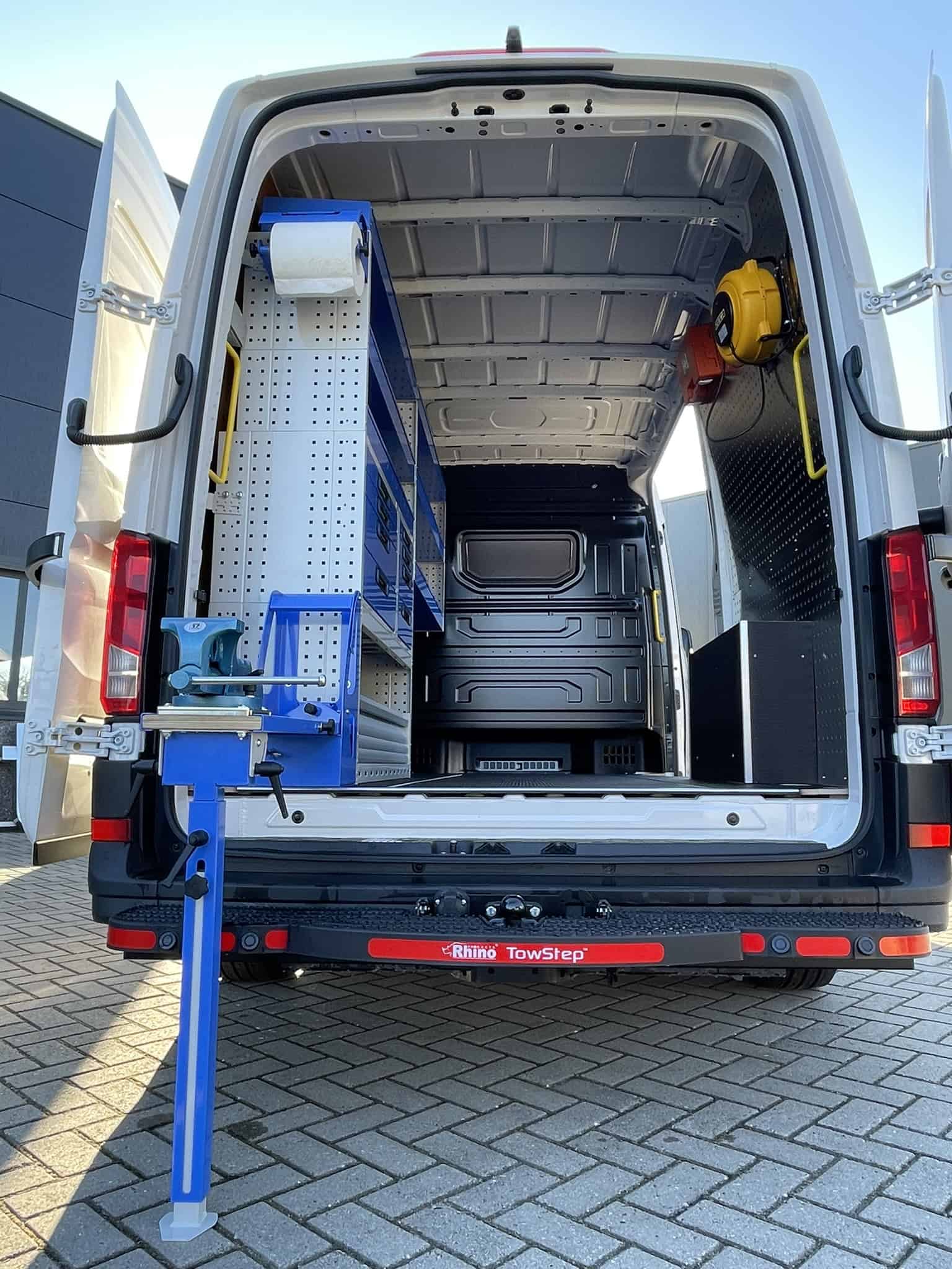Geïntegreerde werkplaatsinrichting in een bedrijfswagen met opbergkasten, gereedschap en werkbank voor efficiënt vakmanschap.