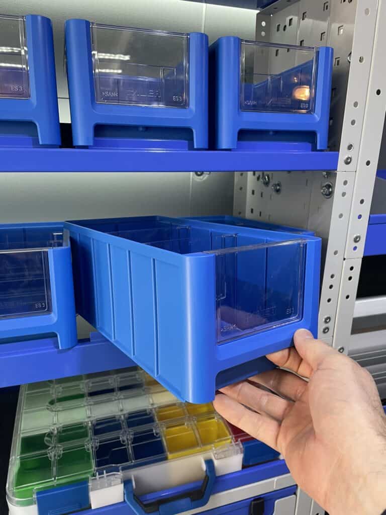 Georganiseerde bedrijfswageninrichting met blauwe opbergdozen voor efficiëntie en overzicht.