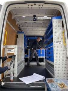 Interieur van een bedrijfswagen met op maat gemaakte opbergsystemen en werkruimte voor technische werkzaamheden.