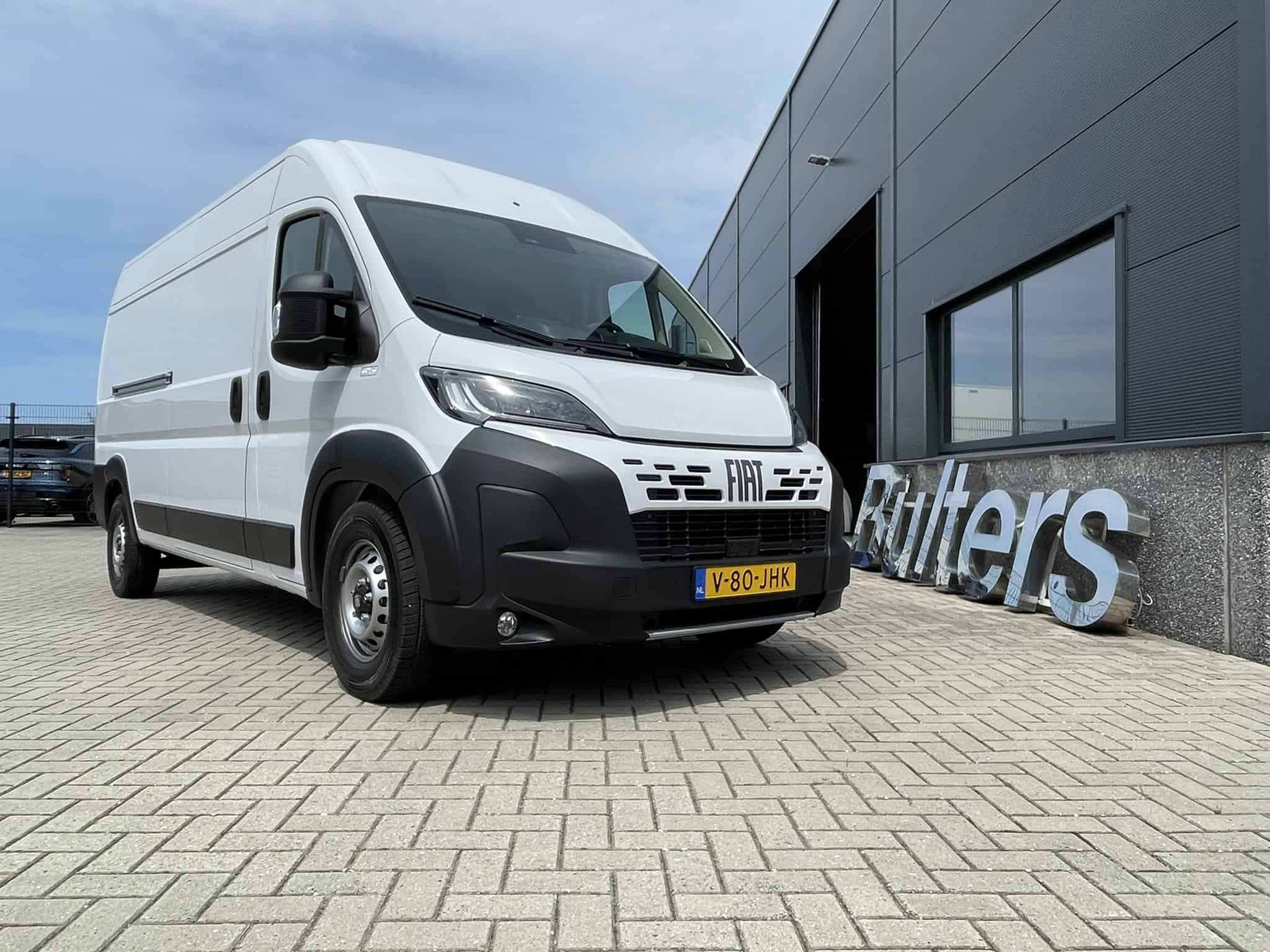 Moderne witte bedrijfswagen geparkeerd voor een bedrijfspand, geschikt voor zakelijke transport en bedrijfsinrichting.