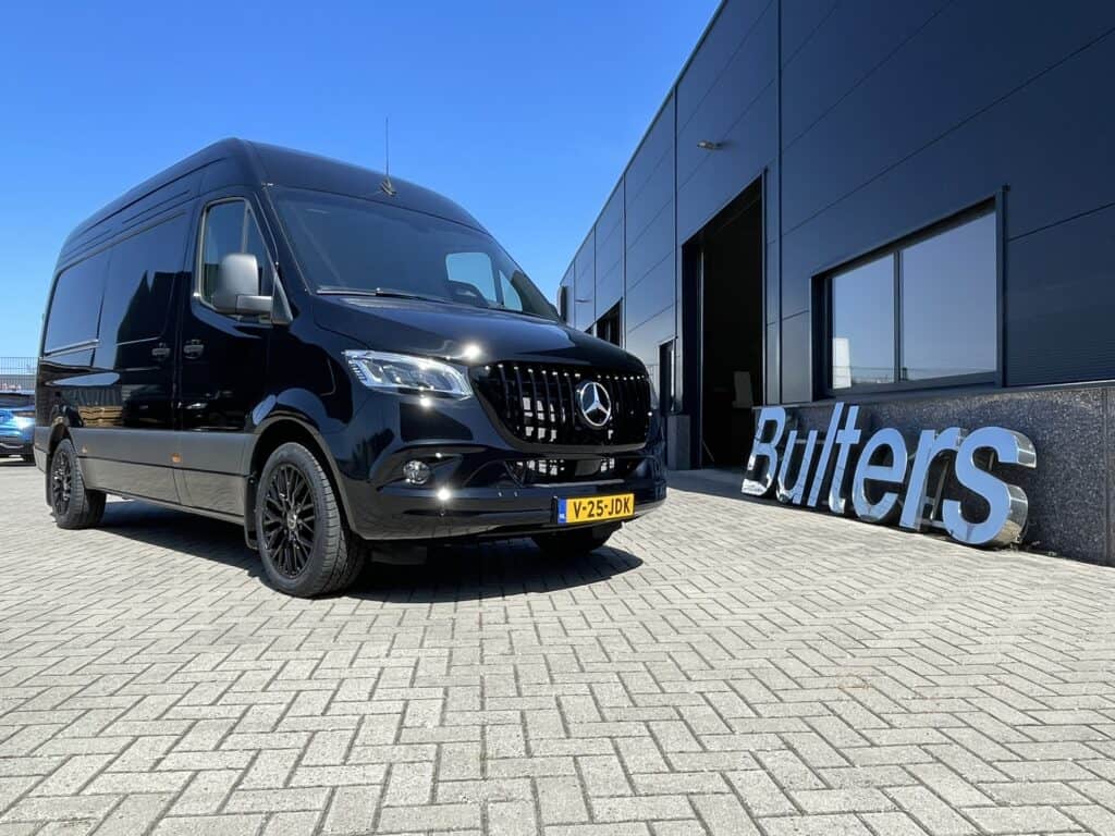 Moderne zwarte Mercedes-Benz bedrijfswagen geparkeerd voor een bedrijfsgebouw, geschikt voor bedrijfsinrichting en transport.