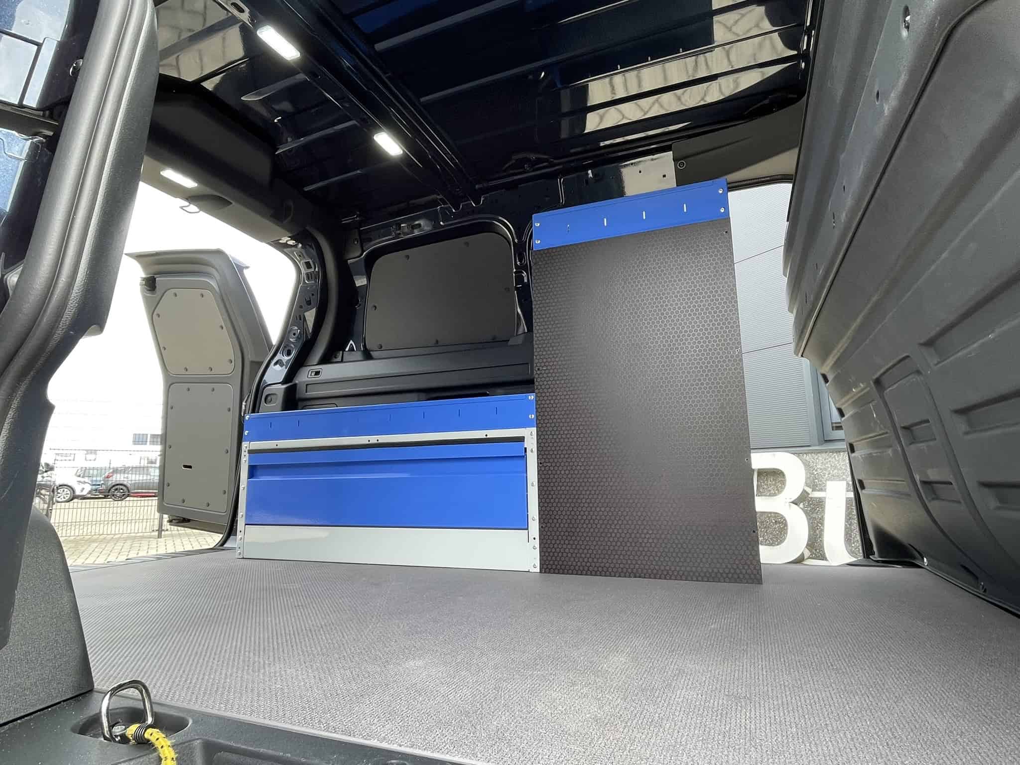 Interieur van een bedrijfswagen met op maat gemaakte opbergkasten en werkblad, ideaal voor professionele toepassingen.