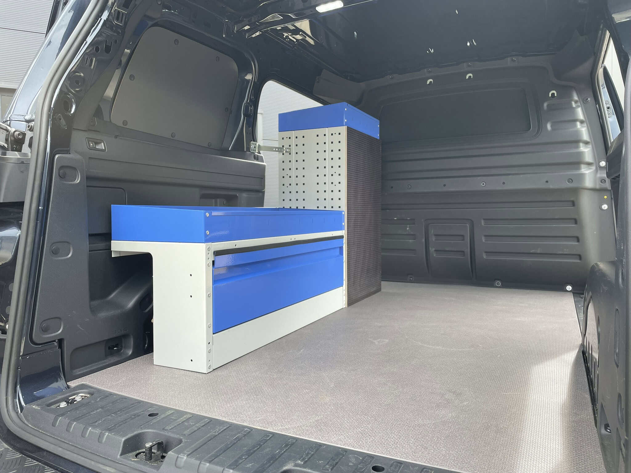 Interieur van een bedrijfswagen met op maat gemaakte opbergkasten en werkblad voor efficiënte bedrijfsvoering.