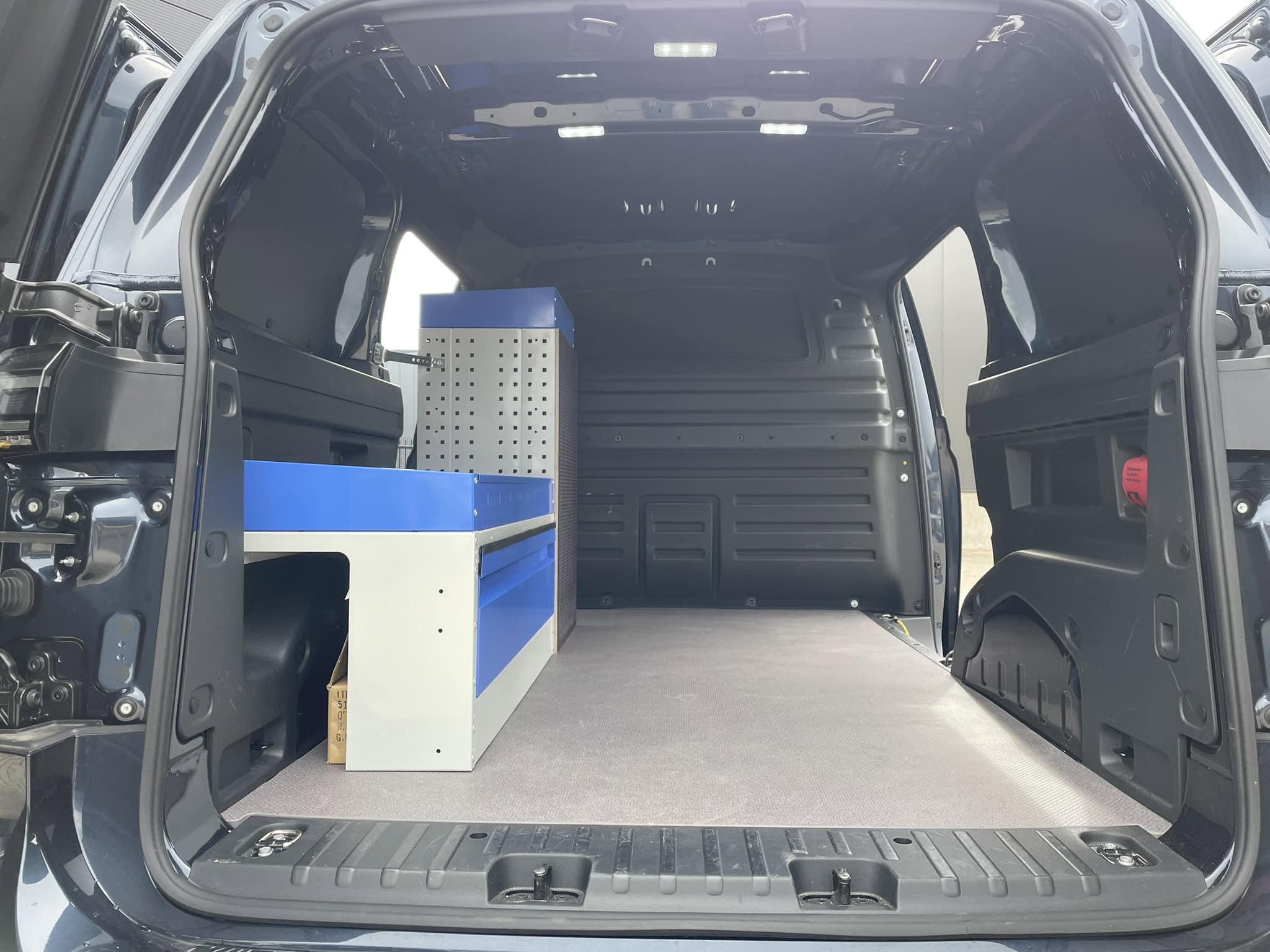 Binnenkant van een bedrijfswagen met op maat gemaakte opbergruimte en werkblad voor professioneel gebruik.