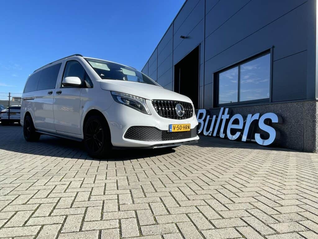 Moderne witte bedrijfswagen geparkeerd voor een bedrijfsgebouw met logo 'Butlers' onder een heldere blauwe hemel.