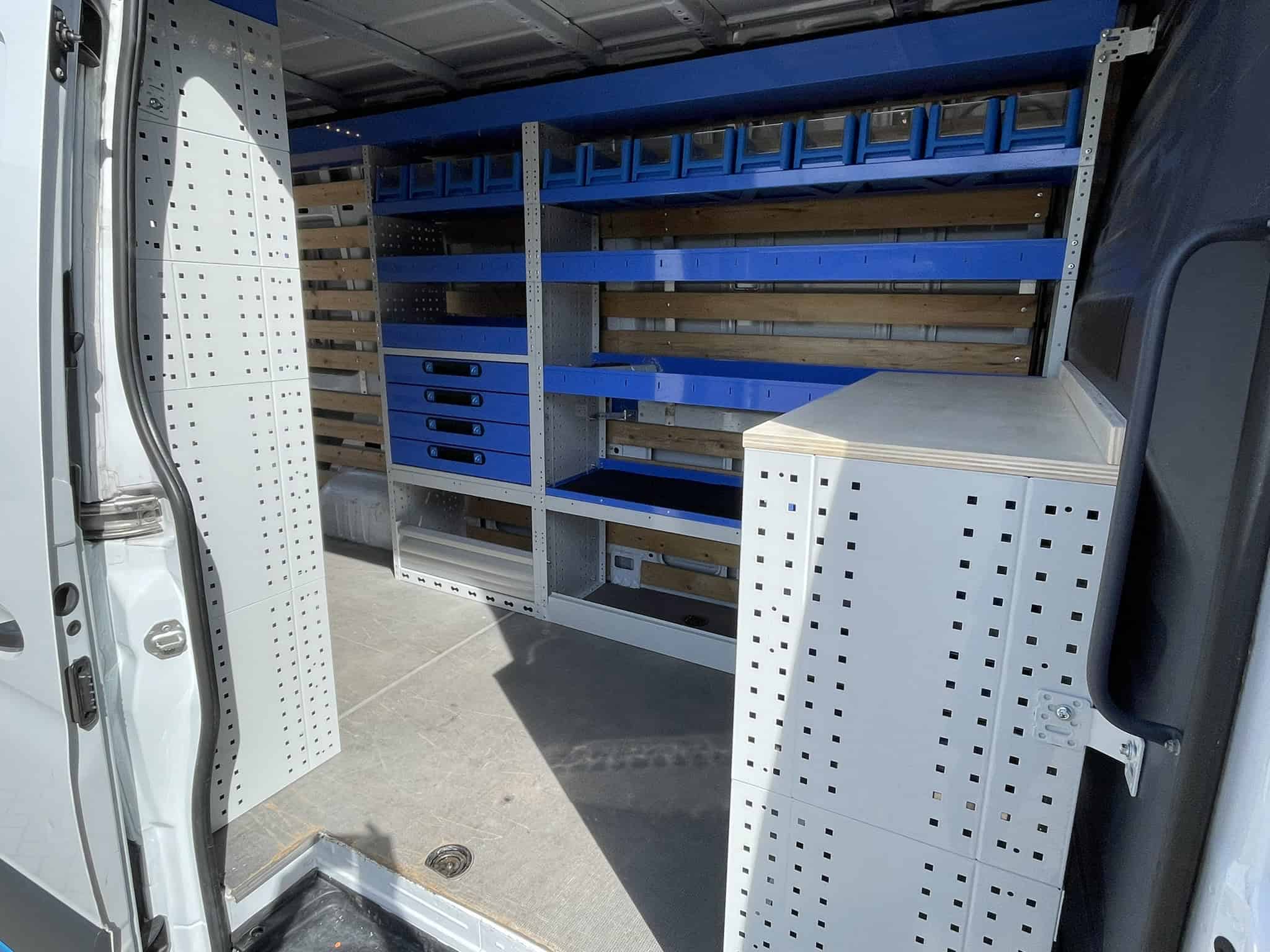 Georganiseerde bedrijfswageninrichting met opbergrekken en werkblad voor efficiëntie.