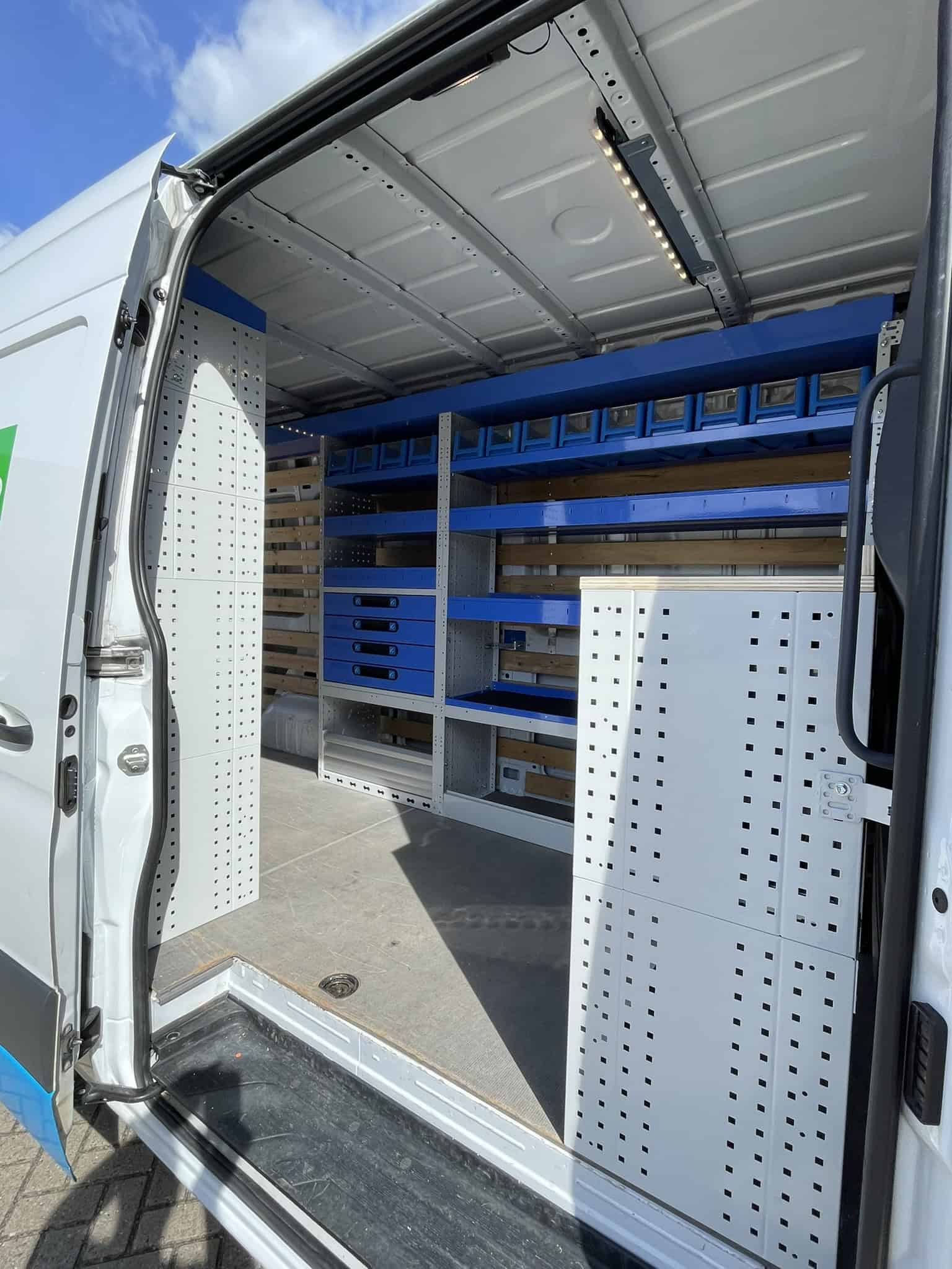 Interieur van een bedrijfswagen met georganiseerde opbergrekken en werkoppervlakken voor efficiënte bedrijfsvoering.