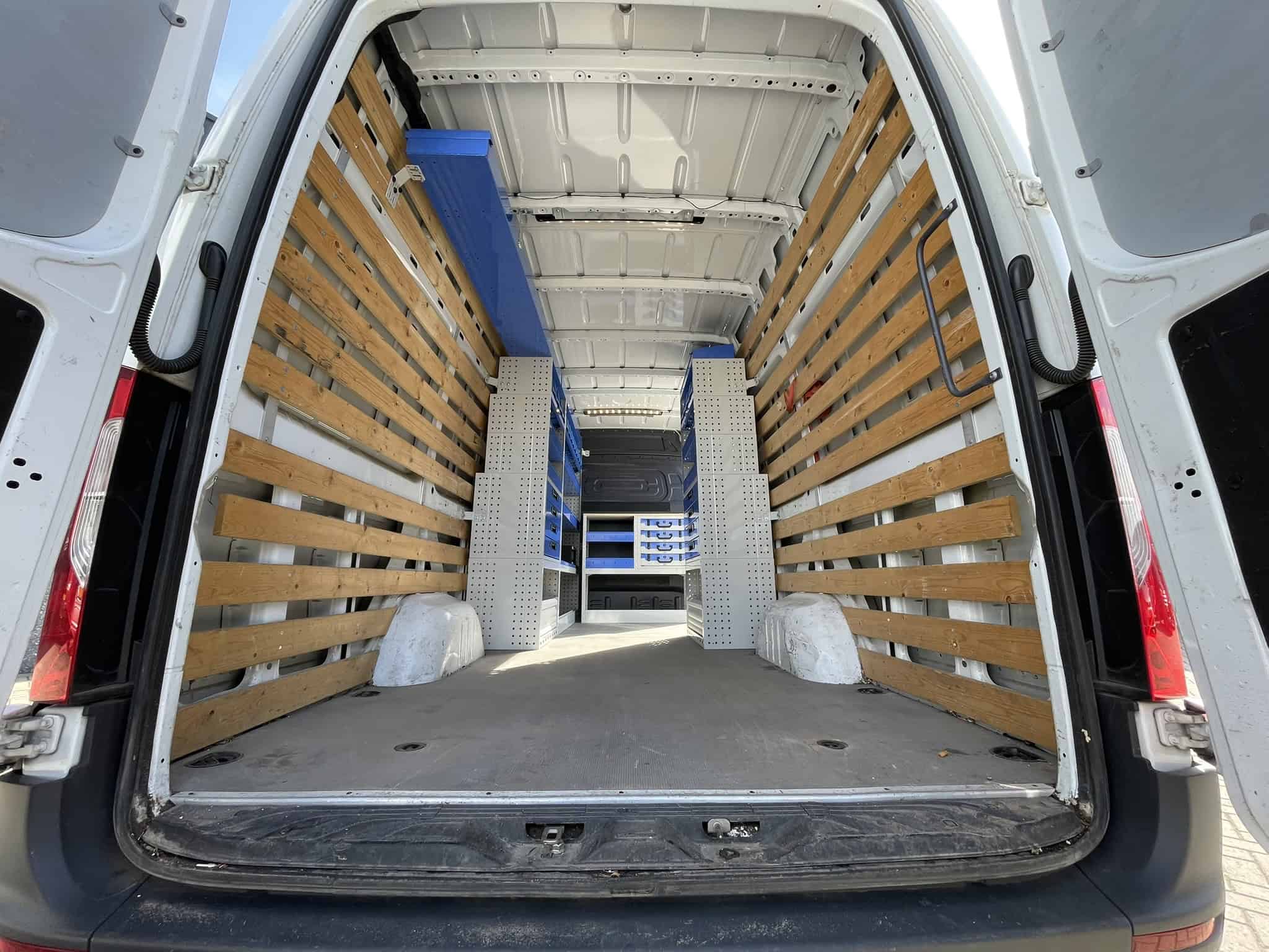 Interieur van een bedrijfswagen met houten wandpanelen en opbergkasten voor efficiënte logistiek.