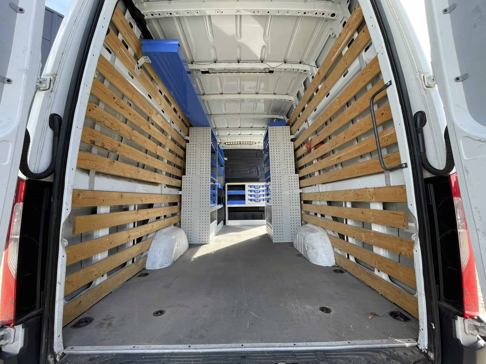 Interieur van een bedrijfswagen met houten en metalen opbergvakken voor efficiënt transport en organisatie.