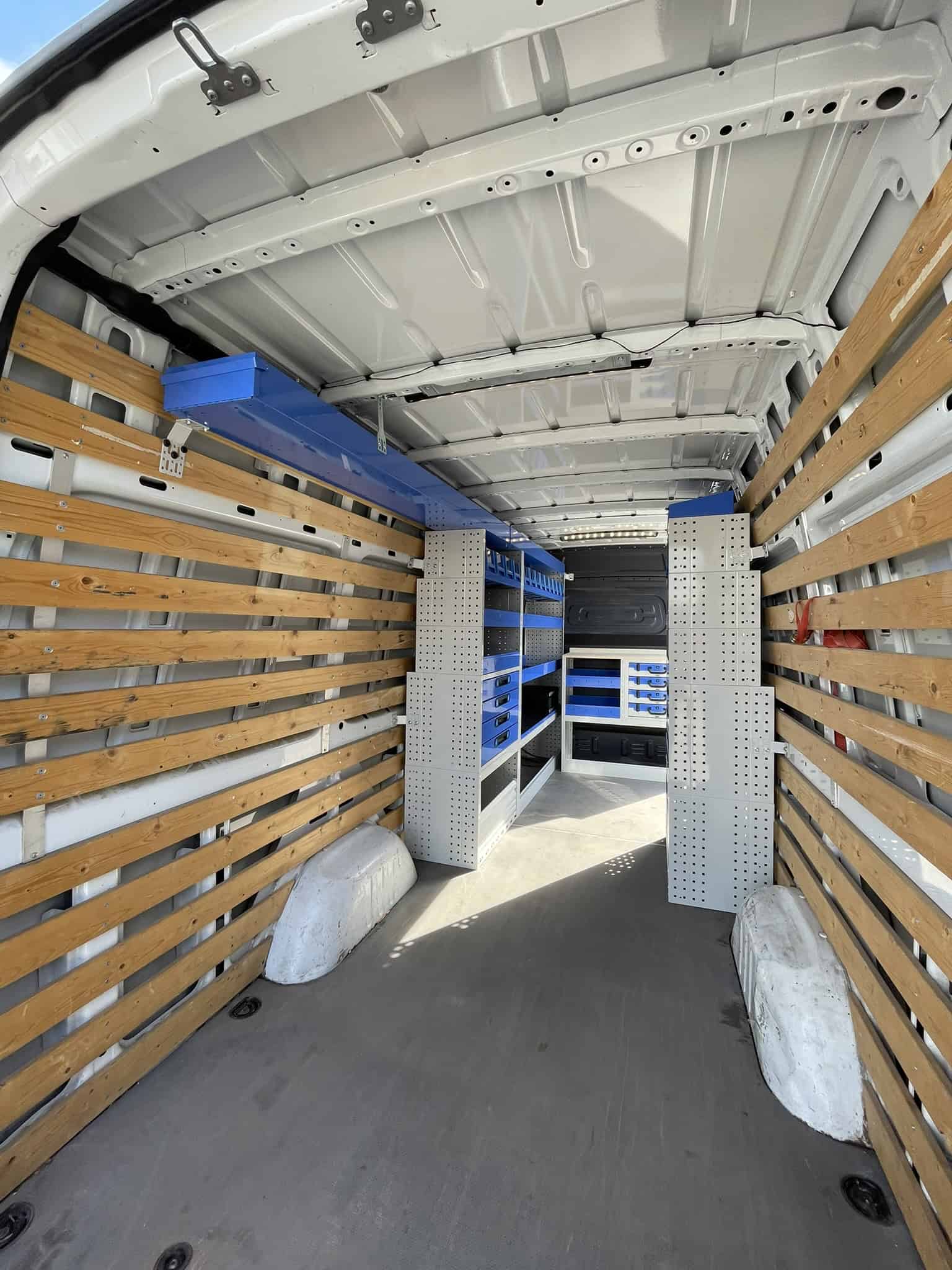 Interieur van een bedrijfswagen met houten wandpanelen, metalen rekken en opbergkasten voor efficiënte opslag en organisatie.