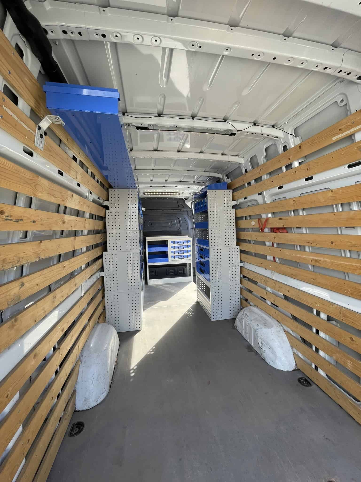 Interieur van een bedrijfswagen met houten wandbekleding en opbergrekken voor efficiënte opslag en organisatie.