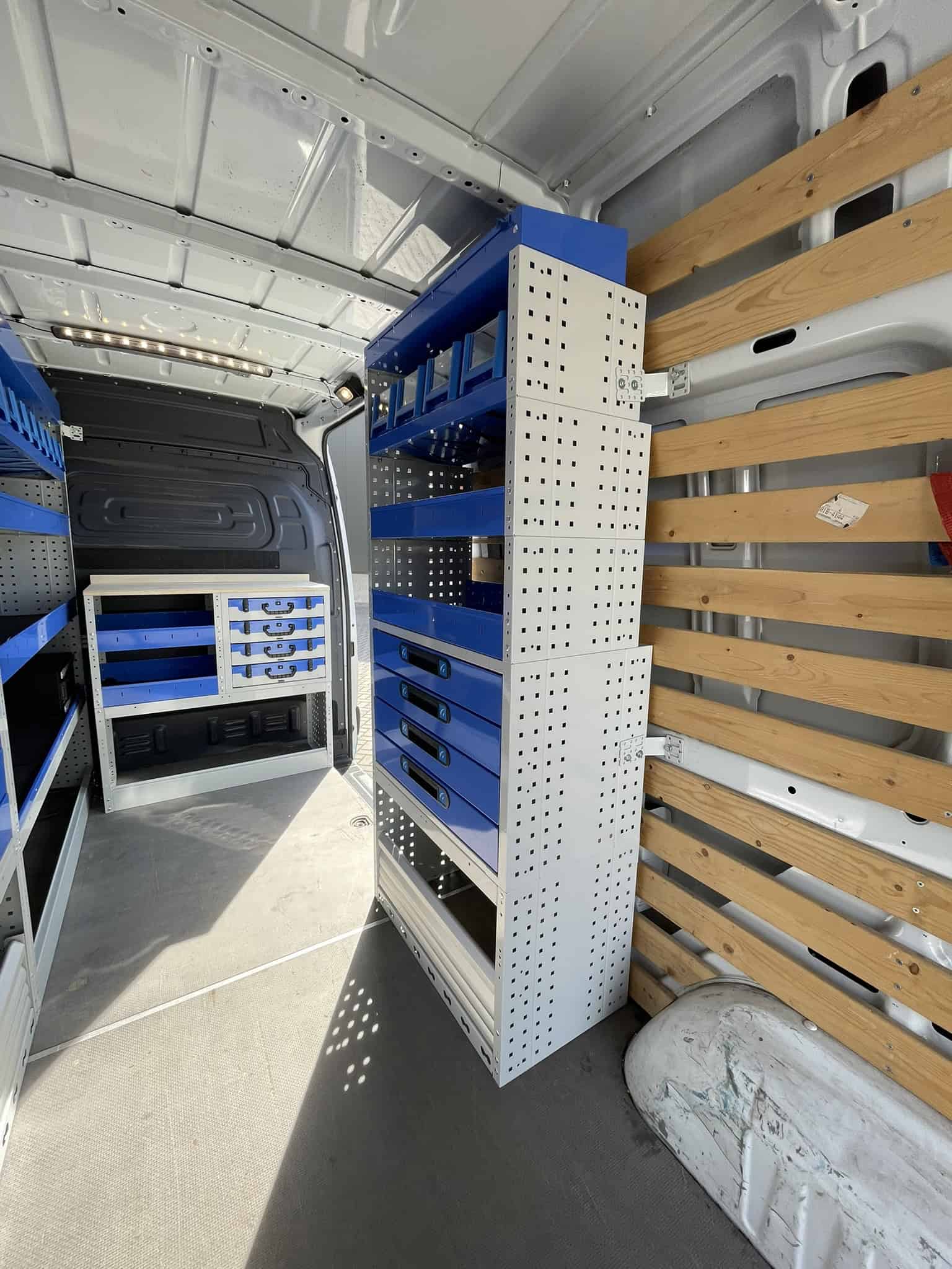 Binnenkant van een bedrijfswagen met op maat gemaakte opbergkasten en houten wandpanelen voor efficiënte opslag.