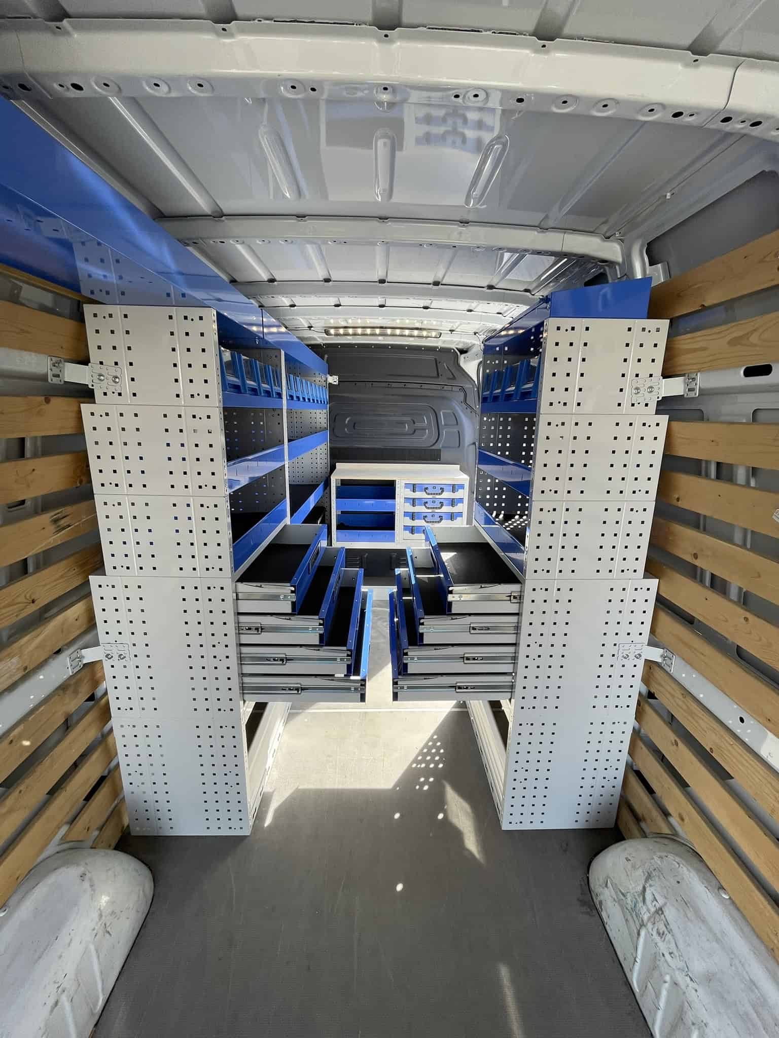 Interieur van een bedrijfswagen met opbergrekken en lades voor efficiënte organisatie van gereedschap en materialen.