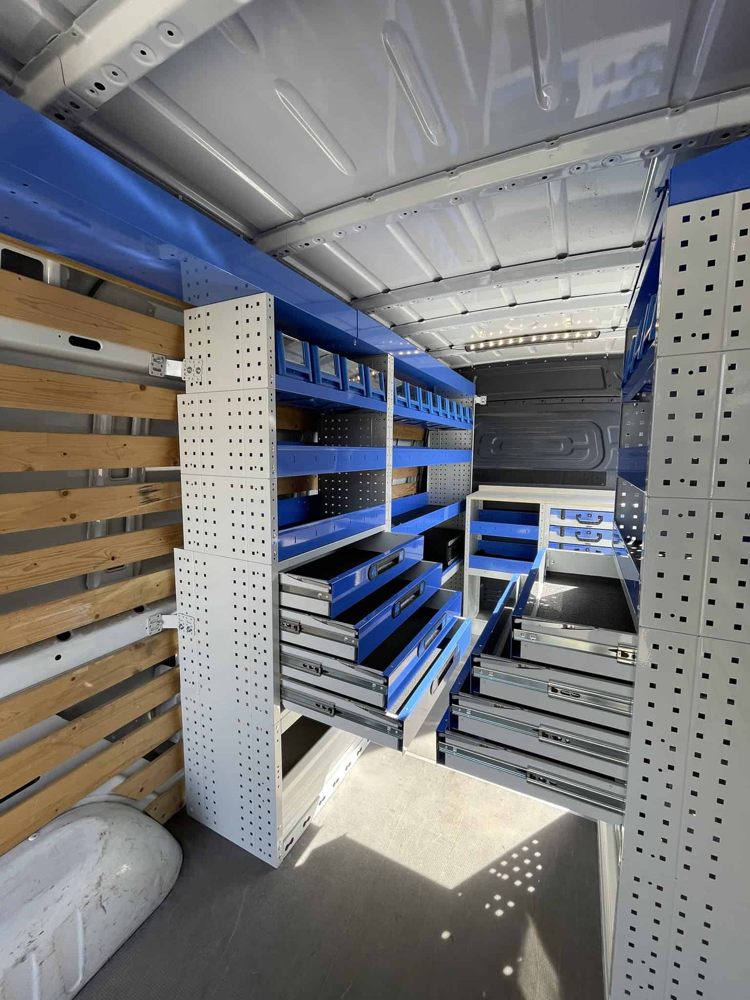 Georganiseerde bedrijfswagen met blauwe en houten opbergkasten en lades voor efficiëntie.