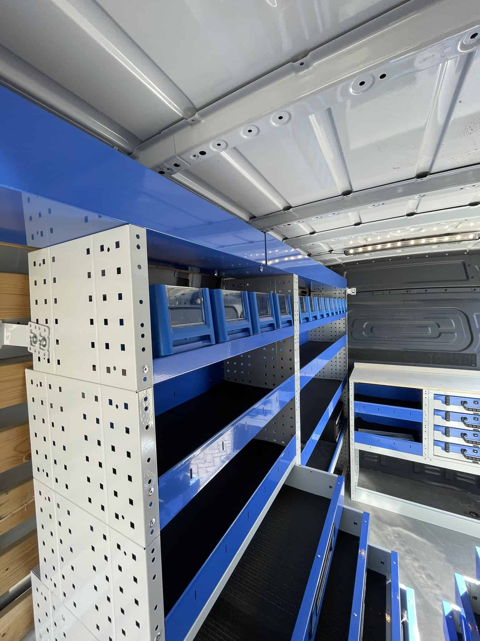 Binnenkant van een bedrijfswagen met opbergkasten en legborden voor efficiënte organisatie en opslag.